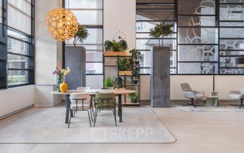 Moderne kantoorruimte in Utrecht Centraal Station met designmeubilair en groene accenten, ideaal voor wie een inspirerende werkplek wil huren.