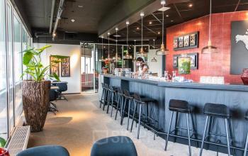 Kantoorpand aan Leidseveer 2-10, Utrecht Centraal Station, modern ingericht met een lange bar, meerdere zitplekken, en een persoon bezig met zakelijke activiteiten.