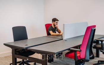 Kantoorruimte huren in Utrecht Centrum aan de Kromme Nieuwegracht 3. Voorzien van flexibele werkplekken met moderne, kleurrijke stoelen. Een man werkt geconcentreerd achter een bureau.
