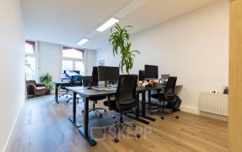 Kantoorruimte huren op Oudegracht 161 in Utrecht Centrum met meerdere bureaus, stoelen en computers in een lichte ruimte met houten vloer.