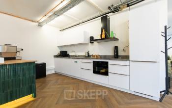 Strakke keuken in kantoorpand Oudegracht 161, Utrecht Centrum, met moderne apparatuur en houten vloer. Ideaal voor huur als onderdeel van kantoorruimte.