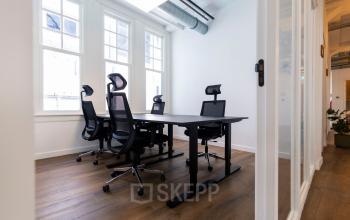 Moderne kantoorruimte te huur in Utrecht Centrum met vier bureaus, ergonomische stoelen en veel natuurlijk licht door grote ramen.