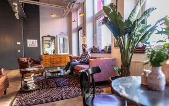 Modern ingerichte loungehoek in kantoorpand aan Nicolaas Beetsstraat 216, Utrecht Centrum, met comfortabele meubels en werkende persoon.