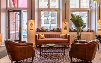 Kantoorruimte huren in Utrecht Centrum aan de Nicolaas Beetsstraat 216, stijlvolle zitruimte met leren fauteuils, bank, kleurrijk tapijt en veel daglicht.