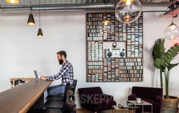 Moderne kantoorruimte aan Nicolaas Beetsstraat 216, Utrecht Centrum, Utrecht met zithoek, bar en design verlichting. Persoon werkt aan laptop aan de bar.