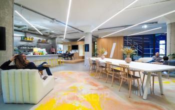 Moderne en creatieve kantoorruimte met open vloerplan op Europalaan 500, Utrecht Kanaleneiland. Twee mensen werken en overleggen aan een grote vergadertafel, omgeven door kleurrijke kunst en moderne verlichting.