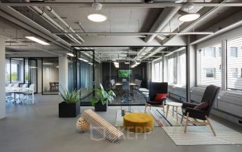 Moderne kantoorruimte met glazen wanden en hoekige details op Europalaan 101, Utrecht Kanaleneiland. Gezellige zithoeken en verlichting creëren een inspirerende werkomgeving.