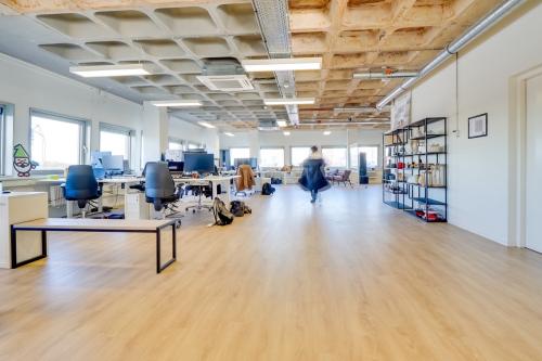 Lichte kantoorruimte op Europalaan 101, Utrecht Kanaleneiland, met moderne werkplekken en bureaus. Een persoon werkt op een laptop terwijl anderen bezig zijn met verschillende werkzaamheden binnen het kantoorpand.