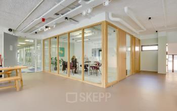 Moderne kantoorruimte huren op Europalaan 93, Utrecht Kanaleneiland. Een fris ingerichte ruimte met glazen wanden en een vergadertafel, waar professionals een bespreking houden in een lichte en open omgeving.