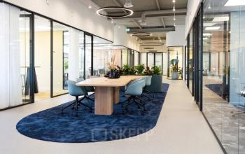 Kantoorruimte huren aan de Atoomweg 50 in Utrecht Lage Weide, met moderne glazen panelen, grote houten tafel en comfortabele stoelen. Sfeervolle verlichting en planten versterken de werkplek.