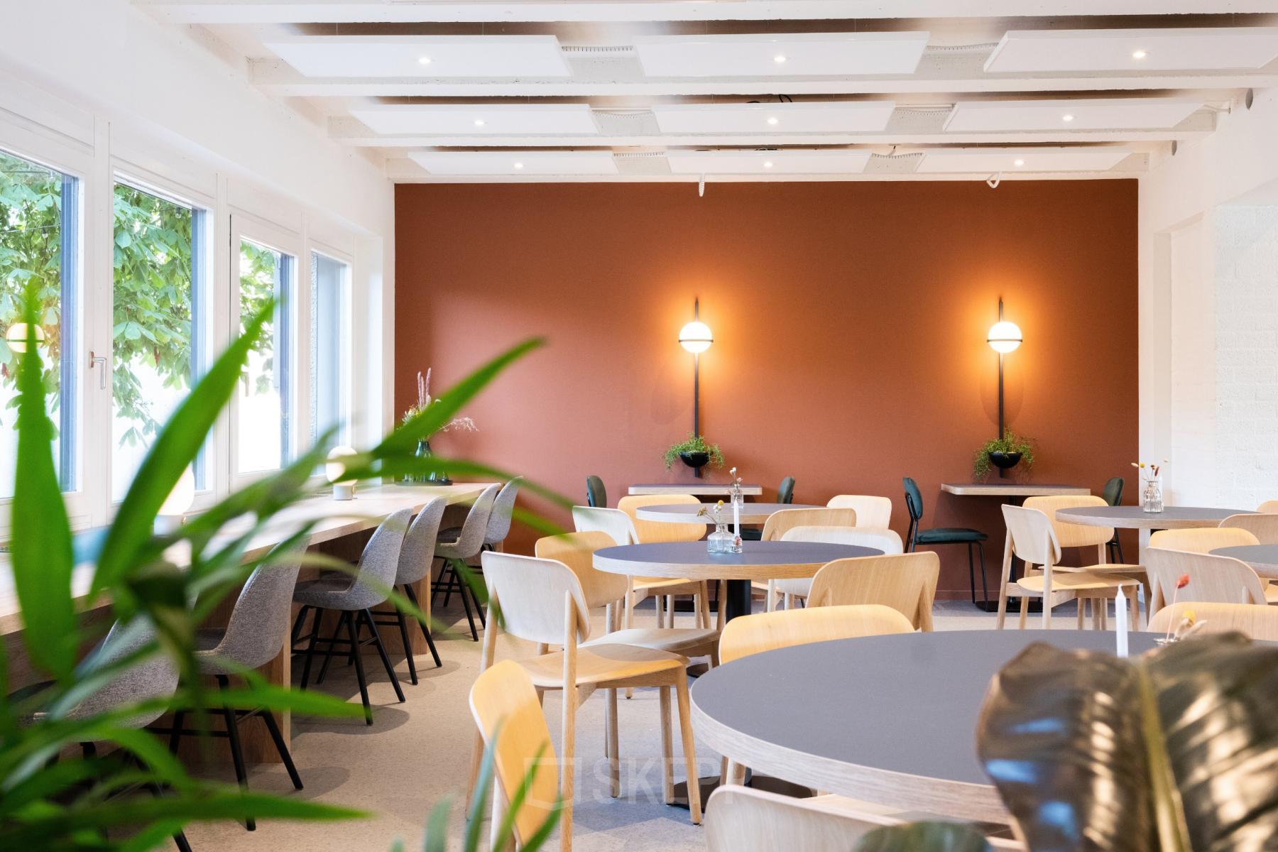 Moderne en uitnodigende bedrijfsruimte met ronde tafels en stoelen in een warme, gezellige sfeer op Atoomweg 50, Utrecht. Ideaal voor evenementen of als gemeenschappelijke werkruimte. Huur geschikt voor diverse bedrijfsactiviteiten.