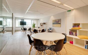 Lichte en moderne kantoorruimte op de Computerweg 22 in Utrecht Lage Weide, met een ronde tafel, stoelen en boekenkasten.