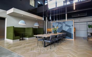 Moderne kantoorruimte in Utrecht Lage Weide met stijlvol meubilair waaronder een lange tafel en groene zitplaatsen, geschikt voor vergaderingen en samenwerking.