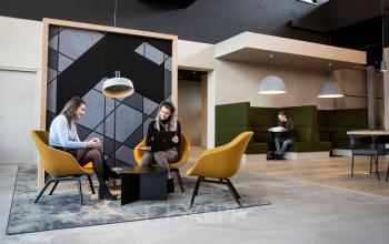 Moderne kantoorruimte huren op Atoomweg 63, Utrecht Lage Weide, met zithoek, trendy interieur en mensen die zakelijke activiteiten uitvoeren.