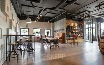 Moderne, ruime kantoorruimte met houten vloeren en industriële elementen op Atoomweg 63, Utrecht Lage Weide, met zitgedeelte en bar.