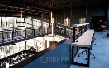 Moderne en strakke kantoorruimte op de bovenverdieping van een kantoorpand aan Atoomweg 63, Utrecht Lage Weide, met zicht op de benedenverdieping, voorzien van lange bureau-opstelling en stoelen. Geschikt voor kantoorruimte huren.