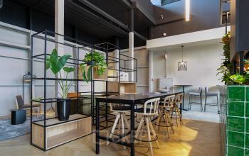 Modern ingerichte kantoorruimte op Atoomweg 63, Utrecht, met hoog plafond, groene accenten en houten meubels. Ideaal voor kantoorruimte huren.