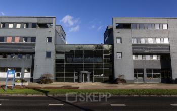 Het kantoorpand aan de Atoomweg 63 in Utrecht Lage Weide toont een modern gebouw met glazen entree en grijze gevel, ideaal voor kantoorruimte huren.