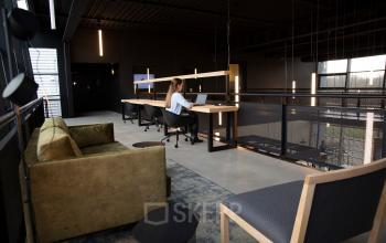 Moderne kantoorruimte op Atoomweg 63 in Utrecht Lage Weide met een ruime werkplek en comfortabele zithoek. Een persoon voert zakelijke werkzaamheden uit aan een bureau.