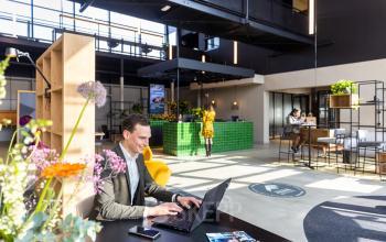 Moderne kantoorruimte te huur op Atoomweg 63 in Utrecht Lage Weide met een stijlvol interieur. Mensen zijn bezig met werken op laptops in een gezellige omgeving met veel daglicht.