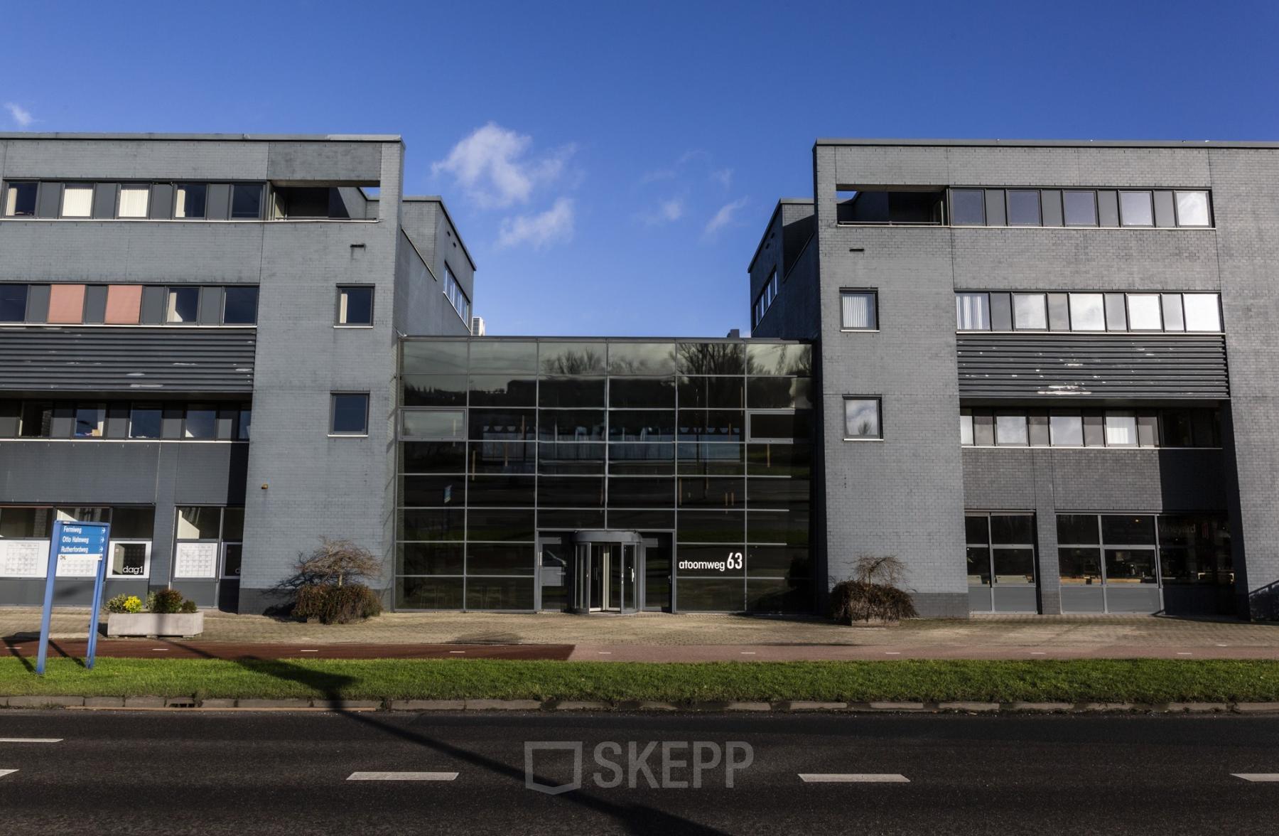Het kantoorpand aan de Atoomweg 63 in Utrecht Lage Weide toont een modern gebouw met glazen entree en grijze gevel, ideaal voor kantoorruimte huren.
