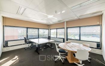 Heldere kantoorruimte op Zonnebaan 45 in Utrecht Lage Weide, met grote ramen, enkele bureaus en stoelen. Perfecte locatie om kantoorruimte te huren voor zakelijke activiteiten in een functioneel kantoorpand.