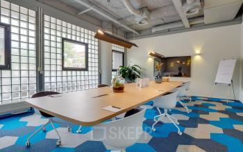 Modern ingerichte kantoorruimte op de Goeman Borgesiuslaan 77 in Utrecht Noord met glazen wanden, kleurrijke vloer en houten accenten voor een professionele uitstraling.