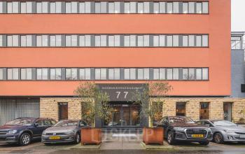 Vooraanzicht van het kantoorpand aan Goeman Borgesiuslaan 77 in Utrecht Noord met parkeerplaatsen voor de ingang. Ideaal voor bedrijven die kantoorruimte willen huren. Strakke architectuur en goed bereikbare locatie.