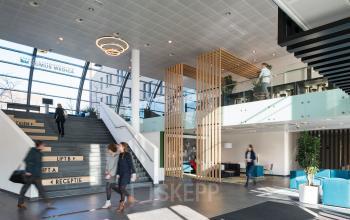 Zakelijke activiteit bij de ingang van het kantoorpand aan Mercatorlaan 1198-2000 in Utrecht Papendorp. Mensen bij de receptie en in gesprek. Ruime en modern ingerichte entree met trappen en zitgedeelte.