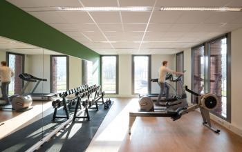 Kantoorruimte huren in kantoorpand op Mercatorlaan 1198-2000 in Utrecht Papendorp met fitnessapparatuur en grote ramen voor daglicht. Een persoon op een loopband en een roeimachine zichtbaar.