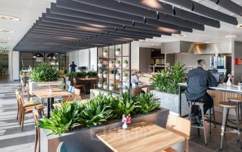 Moderne gemeubileerde kantoorruimte huren in kantoorpand aan Mercatorlaan 1198-2000, Utrecht Papendorp. Personen werken en overleggen in een groen ingerichte werkruimte met tafels en stoelen.