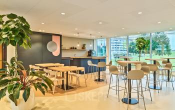 Lichte, gemeubileerde kantoorruimte aan Van Deventerlaan 30-40 in Utrecht Papendorp, met moderne tafels en stoelen en uitzicht op groen buiten. Geschikt voor het huren van een brainstorm- of ontmoetingsruimte.