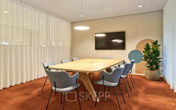 Moderne vergaderruimte in kantoorpand aan Van Deventerlaan 30-40 in Utrecht Papendorp, voorzien van grote tafel, comfortabele stoelen, en een groot scherm aan de muur, ideaal voor kantoorruimte huren.