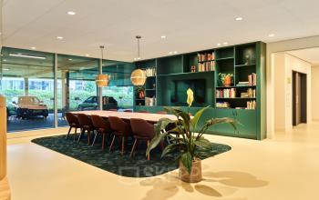 Moderne kantoorruimte huren in Utrecht Papendorp op Van Deventerlaan 30-40 met stijlvolle vergadertafel, boekenwand en groene accenten. Geschikt voor zakelijke bijeenkomsten en te huur in dit veelzijdige kantoorpand.