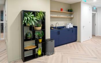 Moderne pantry in kantoorpand Euclideslaan 265, Utrecht Rijnsweerd, voorzien van blauwe kasten en planken, met koffiezetapparaat en planten voor een sfeervolle en functionele omgeving. Ideale plek voor een pauze tijdens kantoorruimte huren.