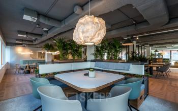 Modern ingericht kantoor met een centrale zitruimte, planten en decoratieve verlichting op Euclideslaan 265 in Utrecht, ideaal voor dynamisch kantoren huren.