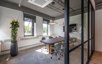 Moderne vergaderruimte met glazen wanden en houten tafel in kantoorpand aan Euclideslaan 265, Utrecht Rijnsweerd. Ergonomische stoelen en natuurlijke verlichting maken het ideaal voor teamvergaderingen. Kantoorruimte huren met een stijlvol en profess