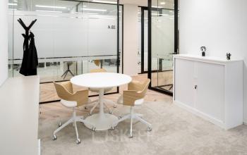 Modern kantoorpand op Euclideslaan 265 in Utrecht Rijnsweerd, met witte ronde tafel en vier stoelen. Glazen wanden met zicht op andere kantoorruimtes, minimale inrichting. Ideale plek om kantoor te huren.