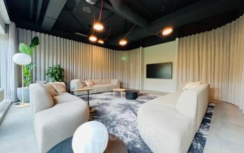 Moderne kantoorruimte op Varrolaan 100-126 in Utrecht Rijnsweerd met comfortabele banken, een groot televisiescherm en sfeervolle verlichting. Ideaal voor informele vergaderingen of ontspanning.
