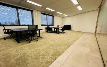 Lichte kantoorruimte op Varrolaan 100-126 in Utrecht Rijnsweerd met grote ramen, groene vloerbedekking en modern kantoormeubilair, ideaal voor werk of vergaderingen.