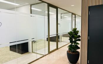 Kantoorruimte op Varrolaan 100-126 in Utrecht Rijnsweerd met glazen wanden, plant en houten wandafwerking. Ideaal voor wie een kantoor of werkruimte wil huren in een aantrekkelijke omgeving.