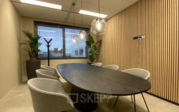 Moderne vergaderruimte in kantoorpand met ovale tafel, zes stoelen en sfeerverlichting op Varrolaan 100-126, Utrecht Rijnsweerd. Perfect voor kantoorruimte huren.