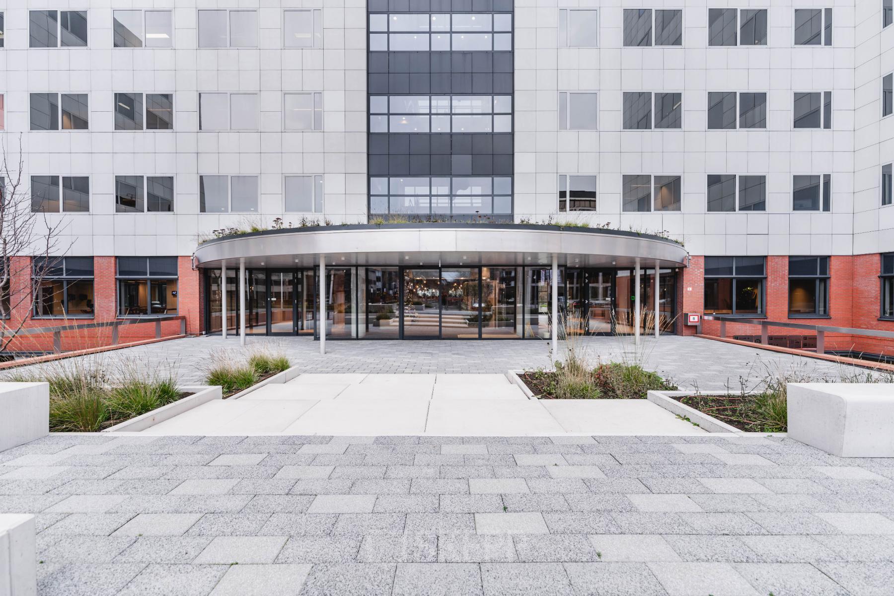 Vooraanzicht van het moderne kantoorpand op Varrolaan 100-126 in Utrecht Rijnsweerd met ruime entree en glazen deuren.