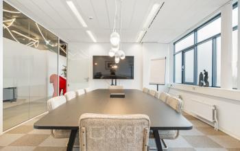 Vergaderruimte in kantoorpand op Daltonlaan 200, Utrecht Rijnsweerd met lange tafel, stoelen en groot scherm. Ideaal voor kantoorruimte huren.