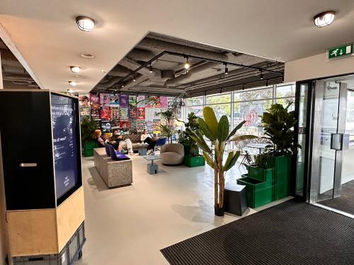 Gemeubileerde kantoorruimte op Daltonlaan 200 in Utrecht Rijnsweerd, met zitgedeelte en planten. Personen zijn bezig met zakelijke activiteiten zoals overleggen en werken op laptops.