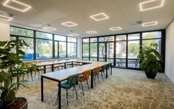 Ruime en lichte kantoorruimte in Utrecht Rijnsweerd met grote ramen en vergadertafels, ideaal voor vergaderingen en samenwerking.