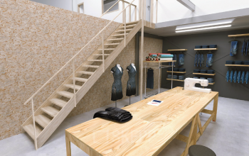 Kantoorruimte met houten trap, werkbank met naaibenodigdheden en kleding opgehangen aan de muur bij Eendrachtlaan 100-260 in Utrecht Zuid.