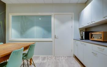 Kantoorpand op Kanaalweg 22, Utrecht Zuid, met een eenvoudig ingerichte pantry voorzien van een houten tafel en mintgroene stoelen geschikt voor kleine vergaderingen of pauzes.