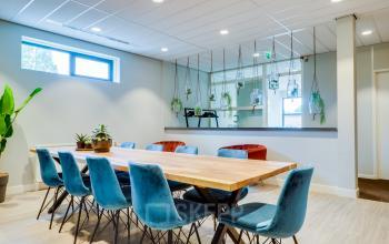 Interieur van een modern kantoorpand gelegen aan Kanaalweg 22 in Utrecht Zuid. Een lichte vergaderruimte met houten tafel, blauwe stoelen en groene planten. Ideaal voor kantoorruimte huren.