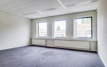 Lichte kantoorruimte met drie grote ramen, grijze vloerbedekking, en witte muren in een kantoorpand aan Kanaalweg 22, Utrecht Zuid. Ruimte is klaar voor verhuur zonder meubels.